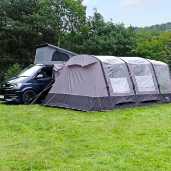 A tent awning pitched next to a van